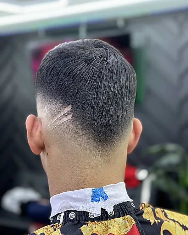 Nuca con degradado y dos líneas diagonales rasuradas detrás de la oreja