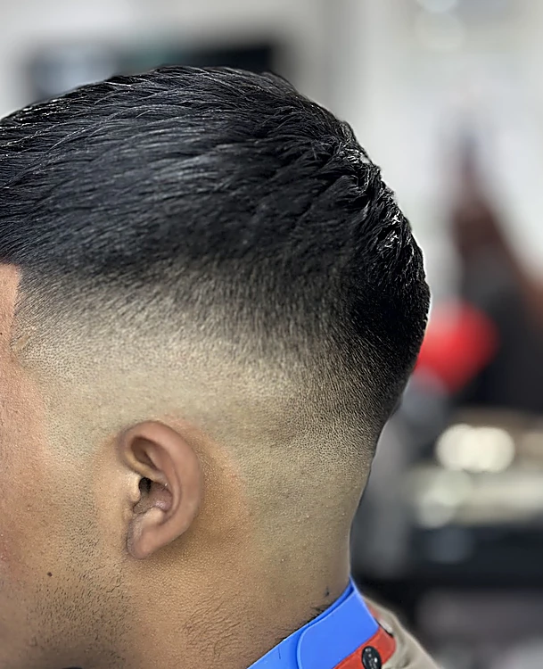 Skin fade visto de costado, del cabello largo arriba a la piel junto a la oreja